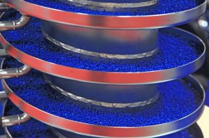spiral conveyor carrying small blue spheres